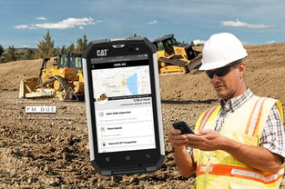 Worker increasing productivity of Caterpillar machinery with handheld device monitoring