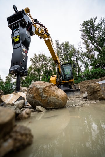 Hydraulic hammer breaking down a rock in the field.